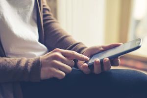 close up of hand woman typing on smart phone at home