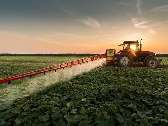 Tractor spraying pesticides on vegetable field with sprayer at spring