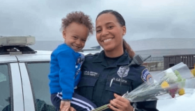 Officer Breann Leath and her child pose in front of a patrol car