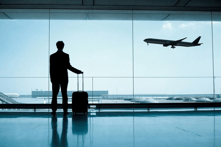 A photo of a traveler looking at a plane that's taking off