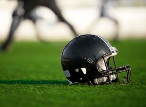 Black football helmet sitting on top of turf