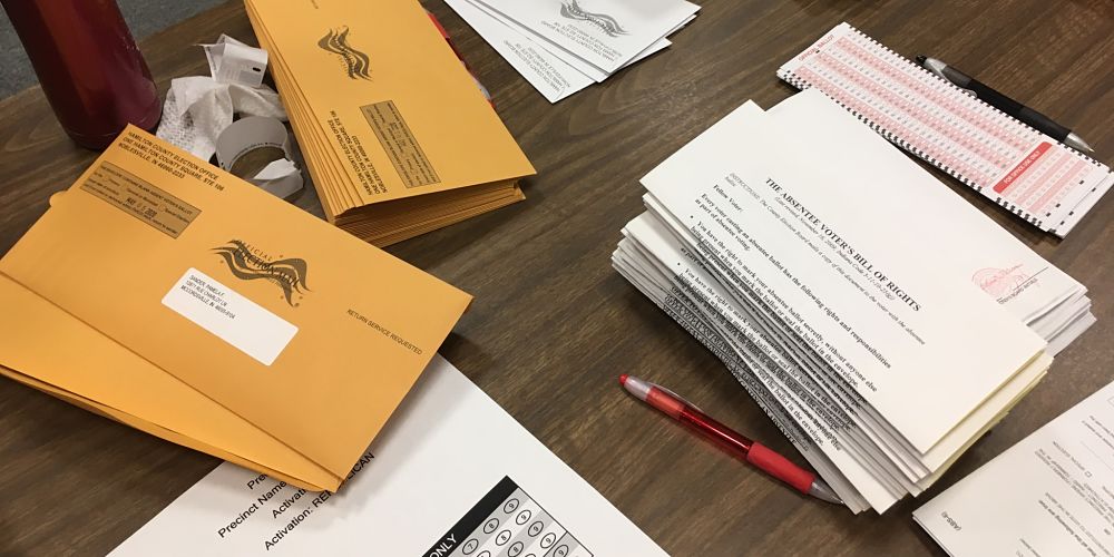 stacks of absentee ballots and envelopes
