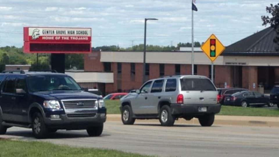Cars driving by the front of Center Grove High School