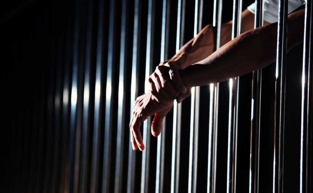 Current image: close up of hand in jail background.