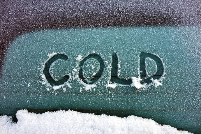 The word "cold" etched into the snow of a car.