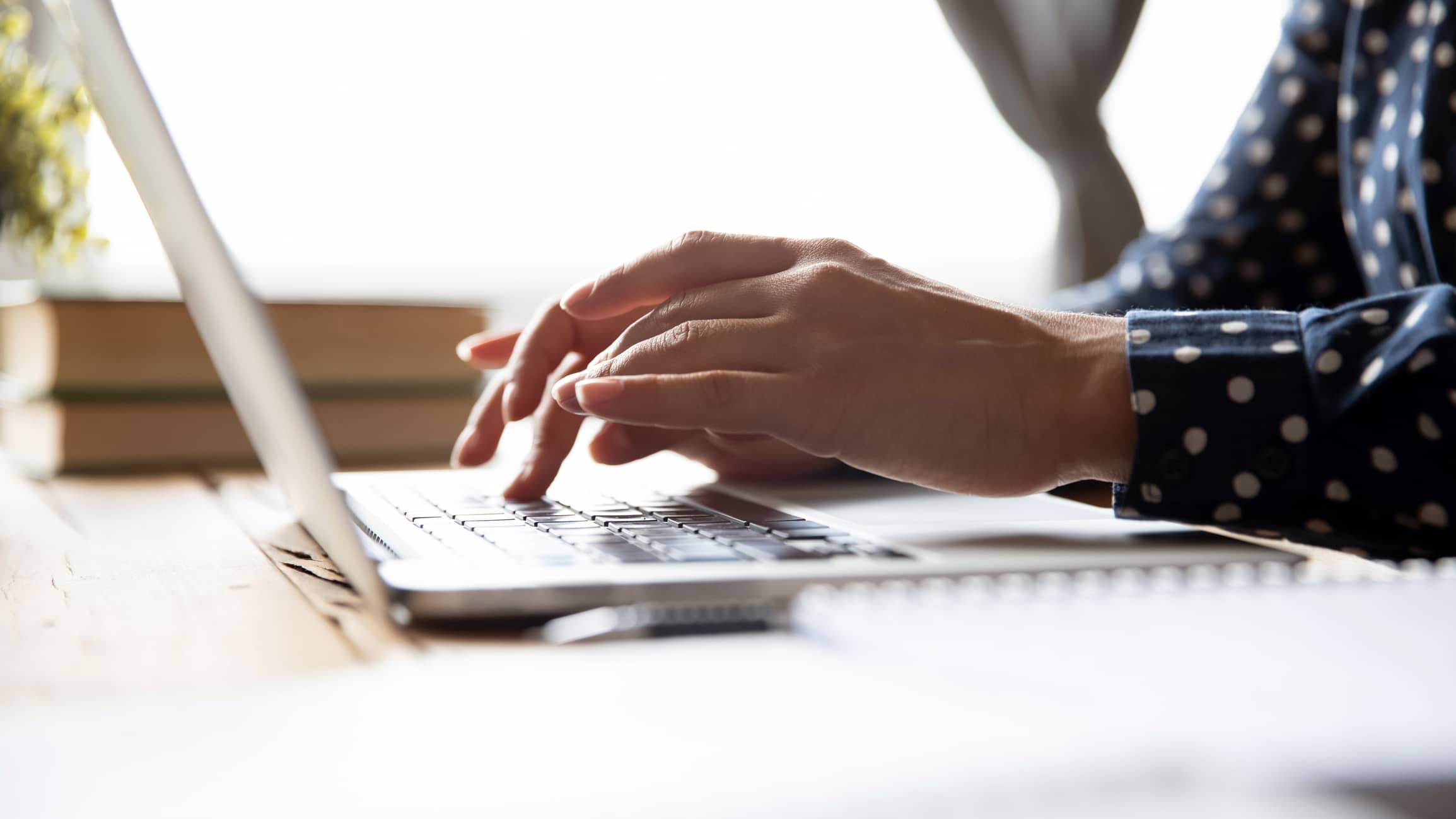 Female hands poised above a laptop keyboard.