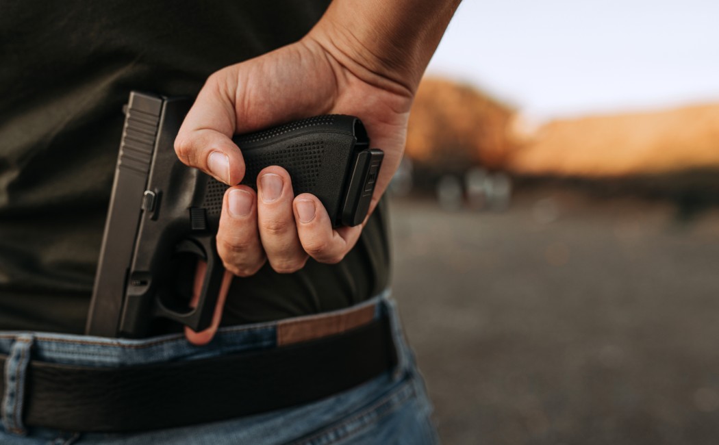 Man holds a handgun, pulling it out of his waistband.