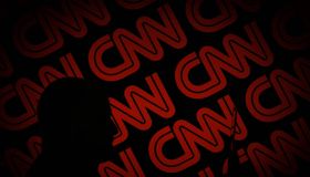 A man is seen holding with a smart device in front of a CNN logo in this photo illustration on 2 July, 2017.