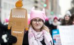 A marcher with a pink hat and pink scarf holds a sign to cover her face that says, "Pussy Grabber" during the Woman's March in the borough of Manhattan in NY on January 18, 2020, USA. The rally took place 3 years after the inauguration of President Donald Trump and 3 days after the Articles of Impeachment were brought to the Senate. Thousands gather to protest equal rights at the 2020 Women's March.