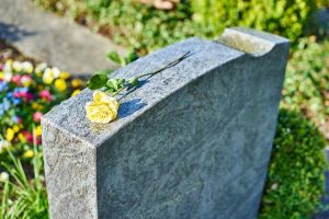 withered yellow rose on gravestone