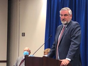 Gov. Eric Holcomb announces creation of a commission to review public health in Indiana, to be chaired by former Noblesville Sen. Luke Kenley (R) and former state health commissioner Judy Monroe (masked, in background).