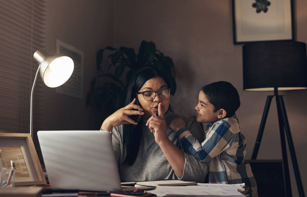 Shot of an adorable little boy demanding his mother’s attention while she works at home