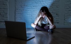 Scared sad girl bullied on line with laptop suffering cyberbullying and harassment feeling desperate and intimidated. Child victim of bullying stalker social media network