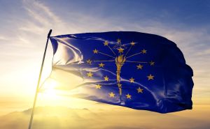 Indiana state of United States flag on flagpole textile cloth fabric waving on the top sunrise mist fog
