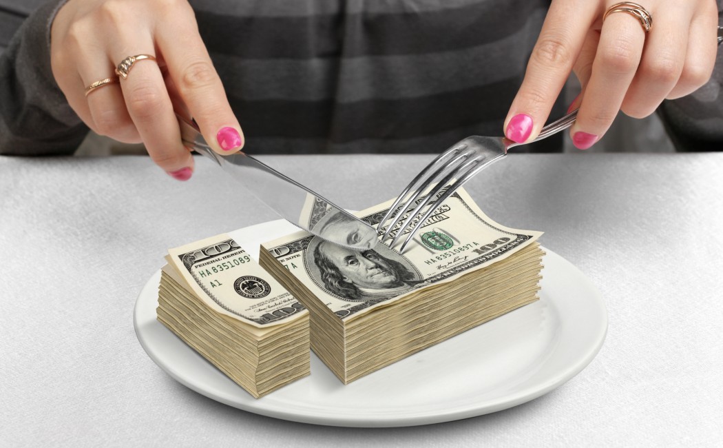 Hands cut money on plate, reduce funds concept