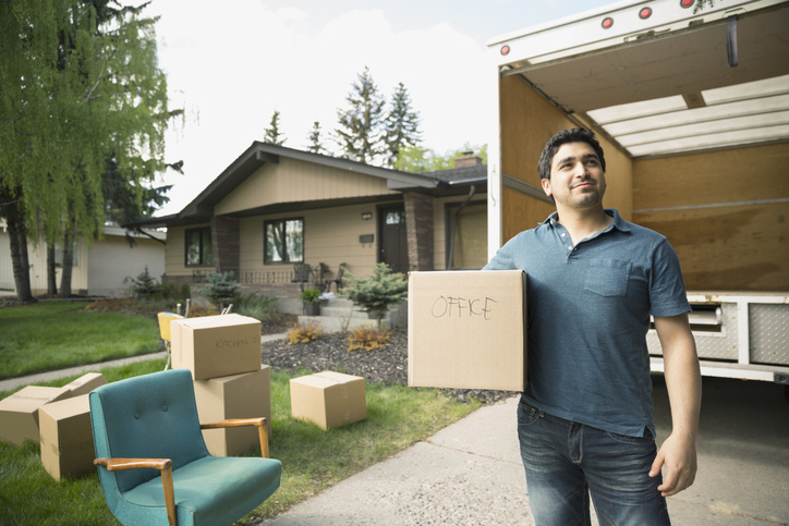 Man holding box outside moving van in driveway