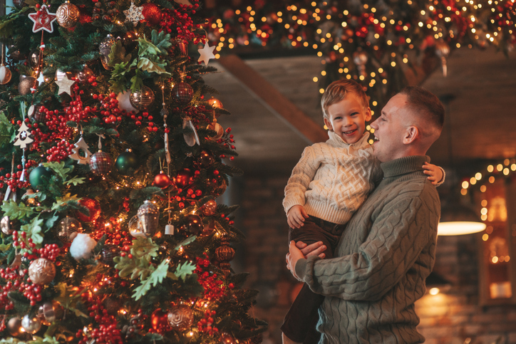 Candid authentic happy dad playing with little son fooling around at wooden lodge Xmas decorated