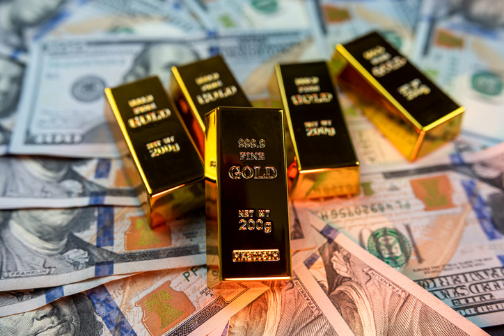 gold bars lie with a calculator near a large sum of dollars isolated.