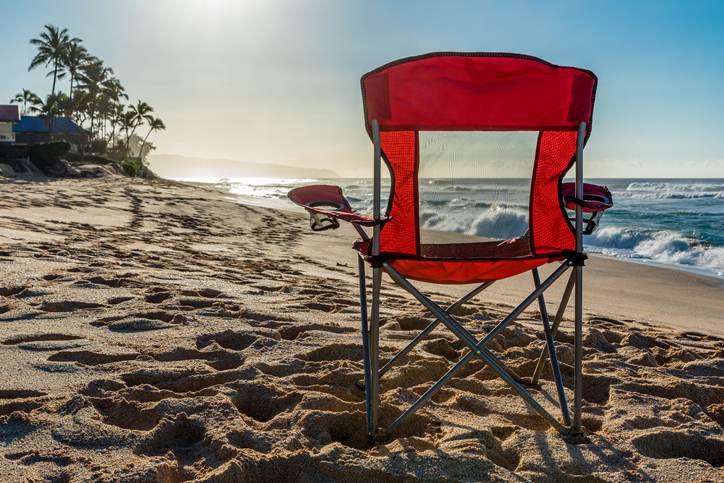 An empty red beach chair facing the sunset on Sunset Beach, Hawaii