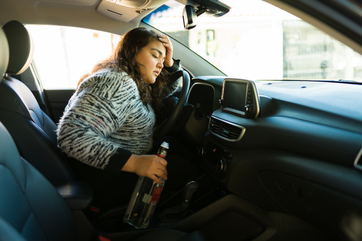 Alcoholic latin woman driving and drinking