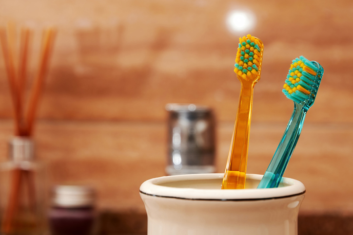 Closeup view of multicolored toothbrushes in the jar on the table in the bath