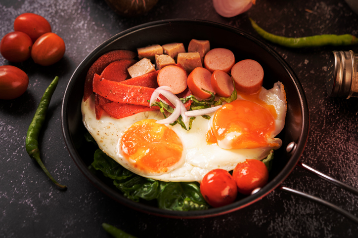 Breakfast with fried eggs,Sausage,And ham in a pan with tomatoes Chili and basil,Romania