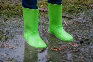 Rubber boots of green color in a puddle