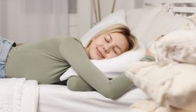 Relaxing young woman lying on pillow in bed. Healthy sleep concept
