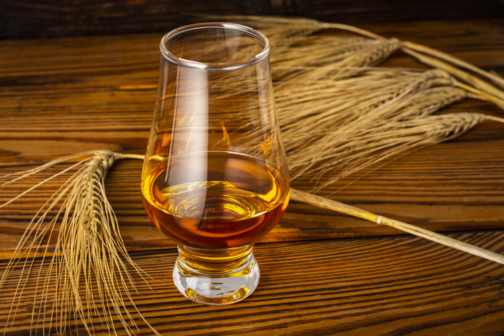 A glass of whiskey on a wooden table.