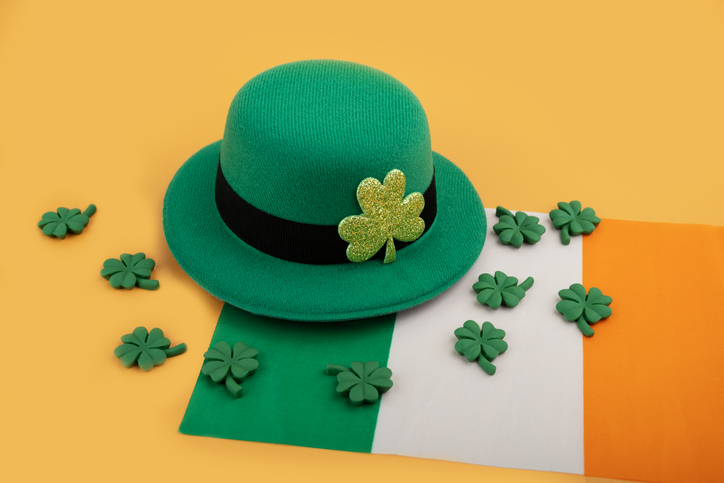 green irish leprechaun hat with shamrocks and irish flag on orange background