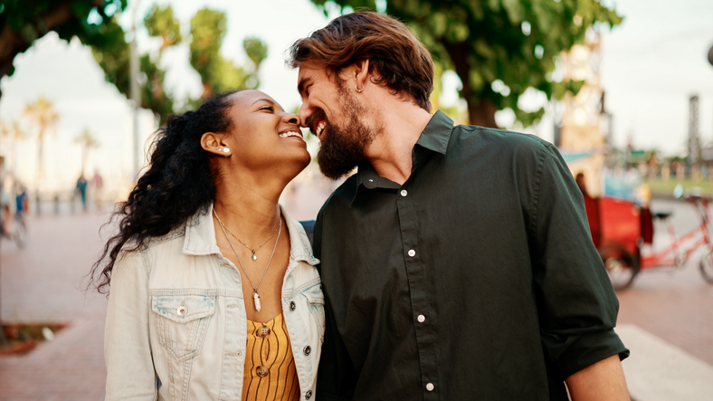 Closeup, man and woman walking smiling holding hands. Close-up of a young interracial couple in love going on a city street