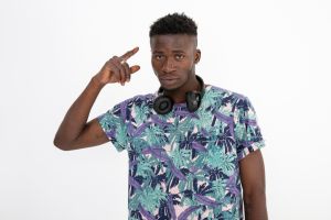 Young black man of African descent wearing patterned and colorful t-shirt, headphones, making different facial expressions.