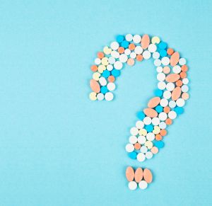The question mark from laid out of medicine pills on blue background.