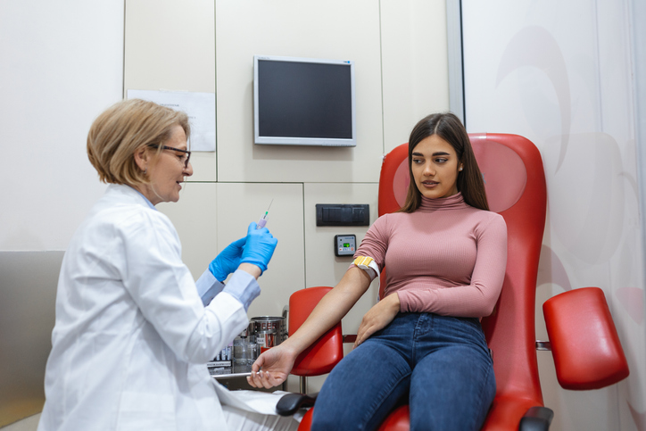 Preparation for blood test by female doctor medical uniform on the table in white bright room. Nurse pierces the patient's arm vein with needle blank tube.