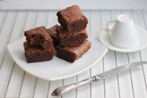 Homemade chocolate brownies stacked on a white plate. Close-up.