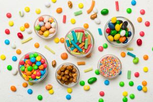 different colored round candy in bowl and jars. Top view of large variety sweets and candies with copy space