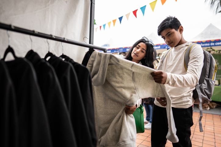 Mother and son choosing a clothes to buy on a market stall