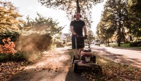 Front view of man mowing grass along sidewalk