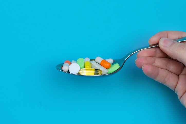 A lot of multicoored pharmaceutical medicine tablets, pills and capsules in spoon. Concept of excess medication, health care, dietary supplements and depression.