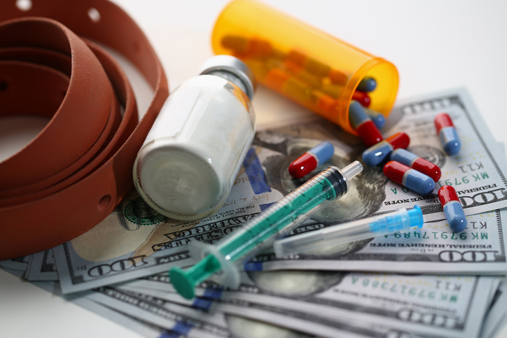 Medical syringe with white cocaine powder and medical pills on dollar bills