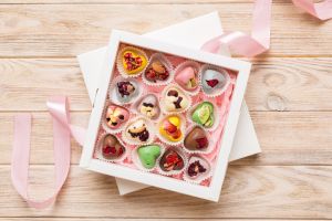 Holiday composition: sweet candy, with gift boxes with bow and chocolate hearts, photo template, background. Top View with copy space on colored background
