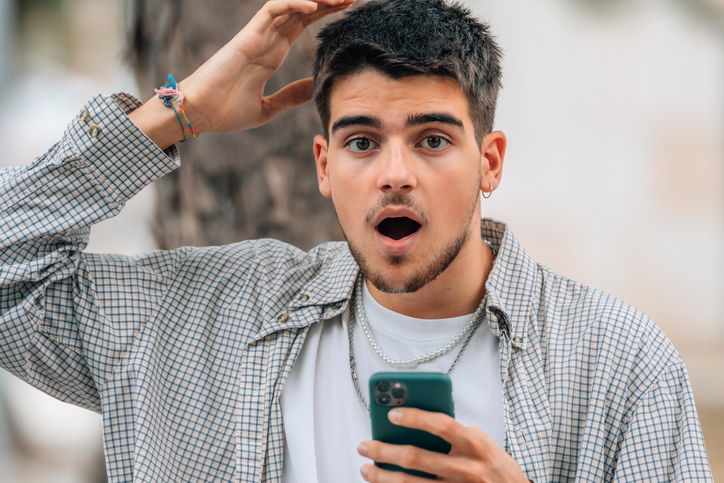 young man with mobile phone astonished
