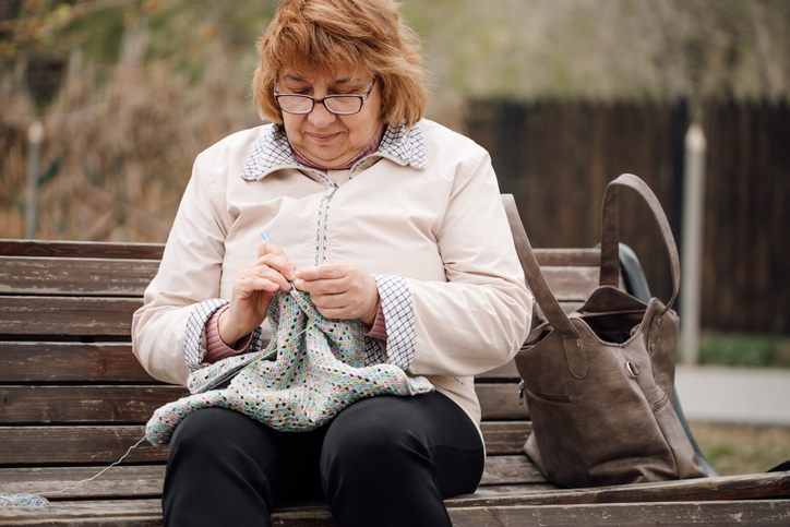 Park bench providing perfect spot for elderly woman to knit