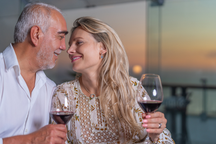 Elegant couple about to kiss while drinking wine during sunset