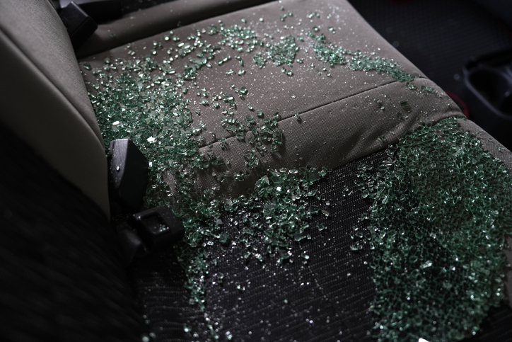 Shards of broken glass lie on the seats of a car