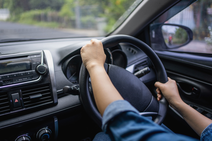 Female hands on the steering wheel of a car while driving. Close-up of a woman's hand driving a car