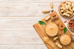 Bowl of peanut butter and peanuts on table background. top view with copy space. Creamy peanut pasta in small bowl