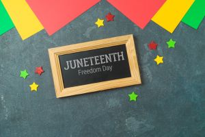 Juneteenth holiday day background with colorful paper, chalkboard sign and stars. Top view, flat lay