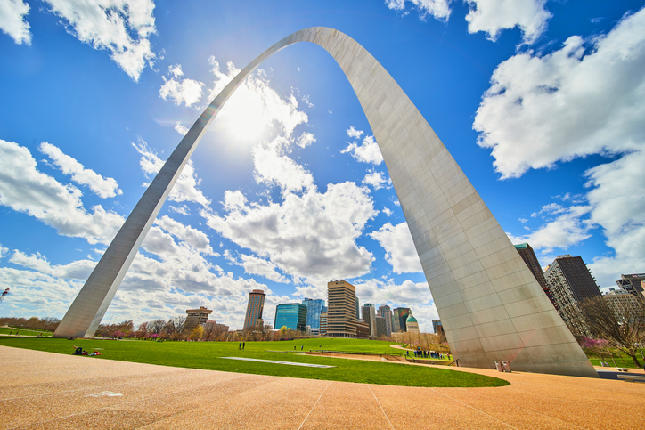 Skyline viewed under St. Louis Gateway Arch with vibrant sky and sun
