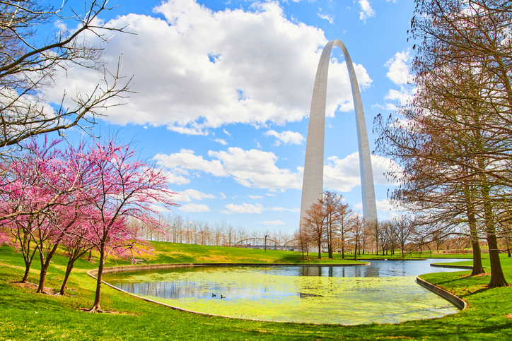 Gateway Arch in St. Louis by lake lined with cherry trees in early spring